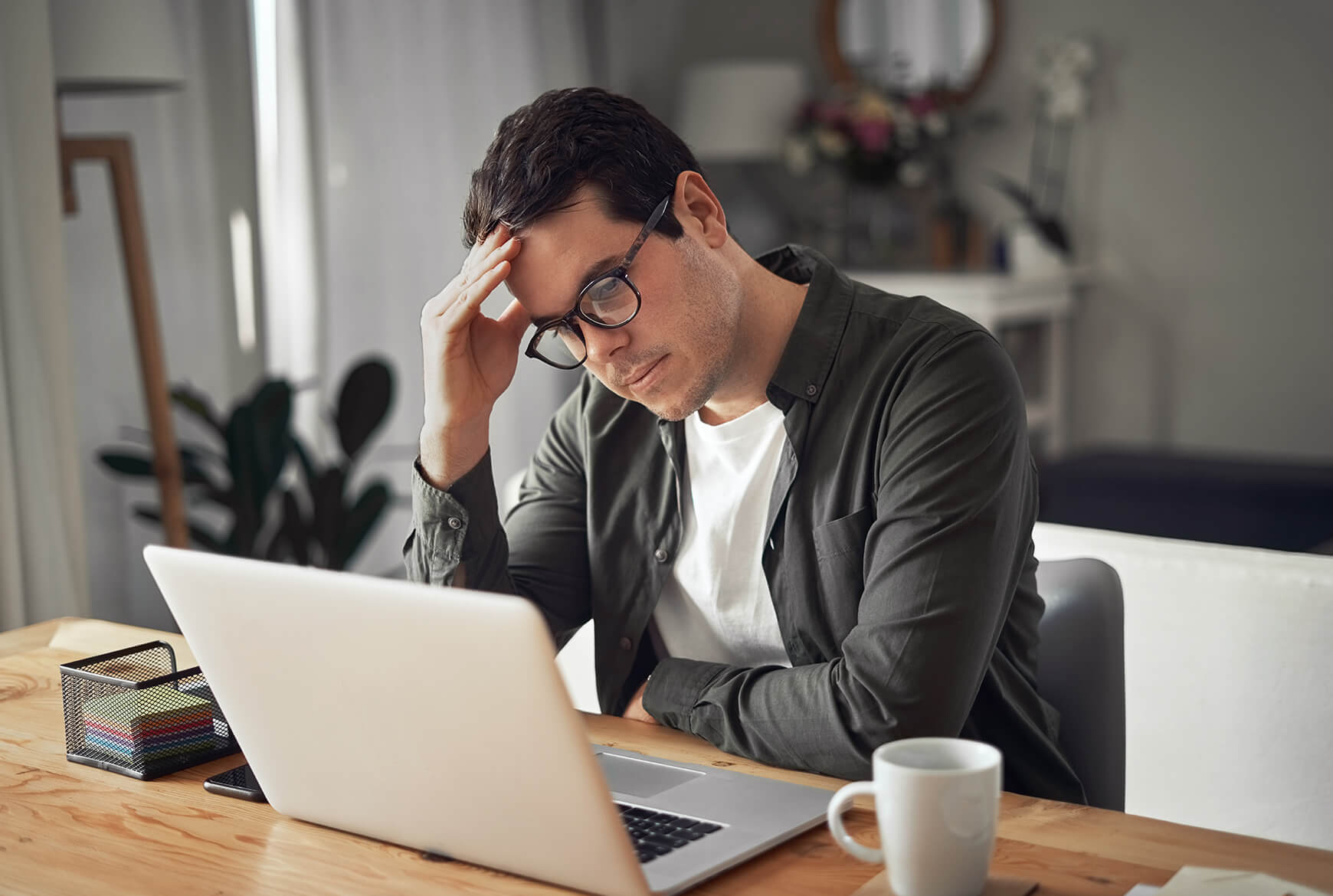 Homme tenant sa tête devant un ordinateur portable