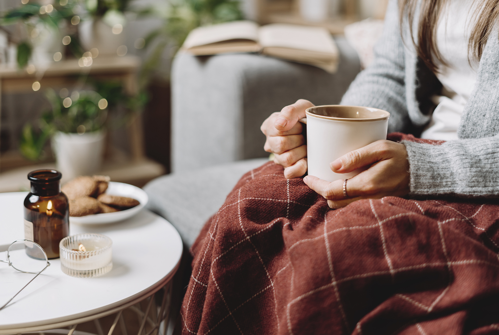 Une personne est assise sur un divan et tient une tasse dans les mains