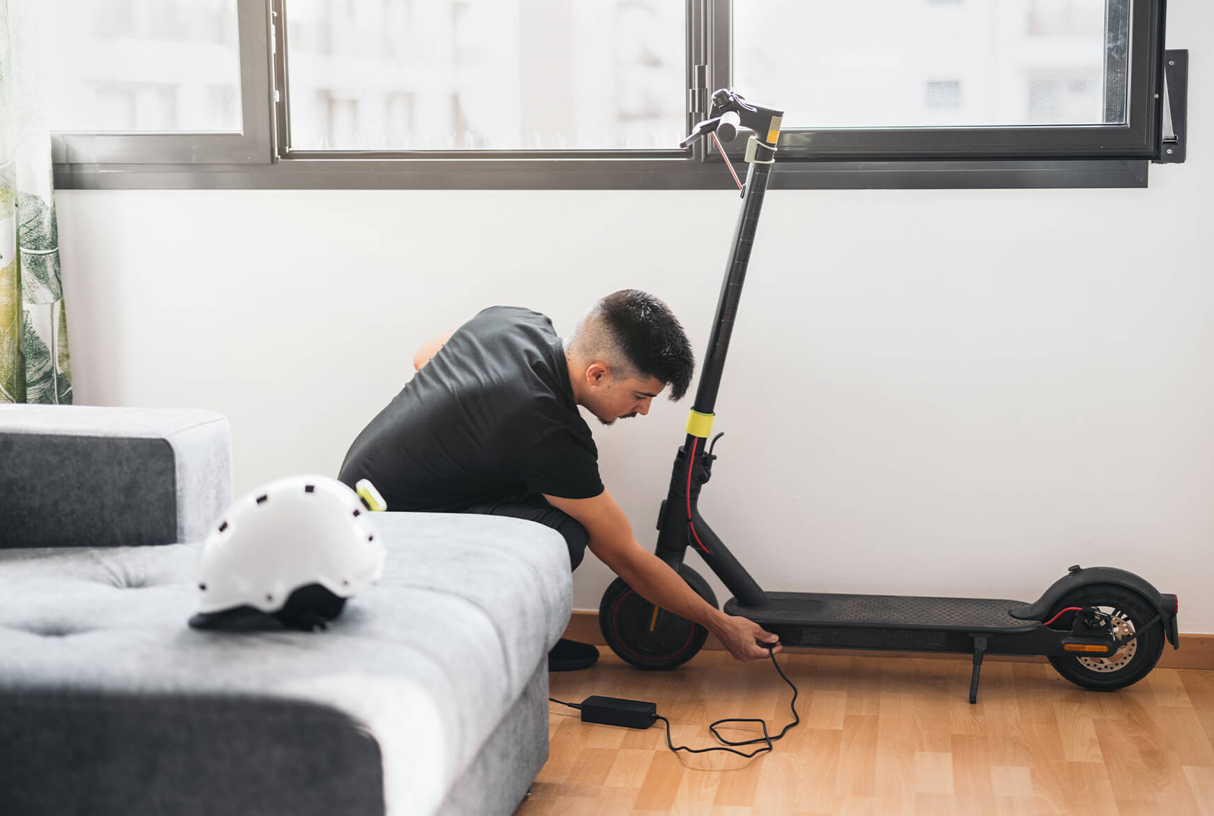 Un homme recharge sa trottinette électrique