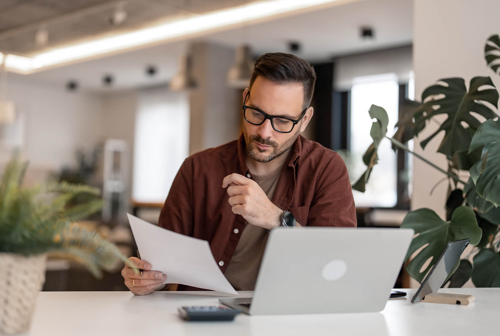 Un homme regarde des papiers devant son ordinateur