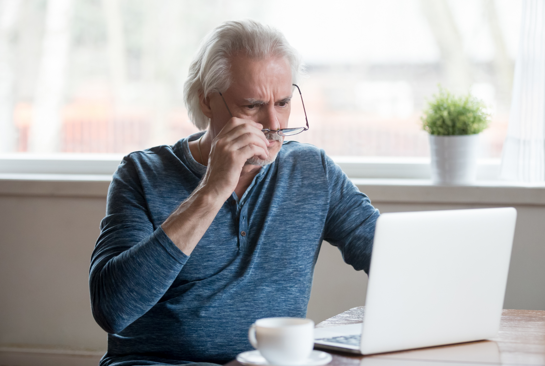 Un homme âgé consulte un ordinateur portable