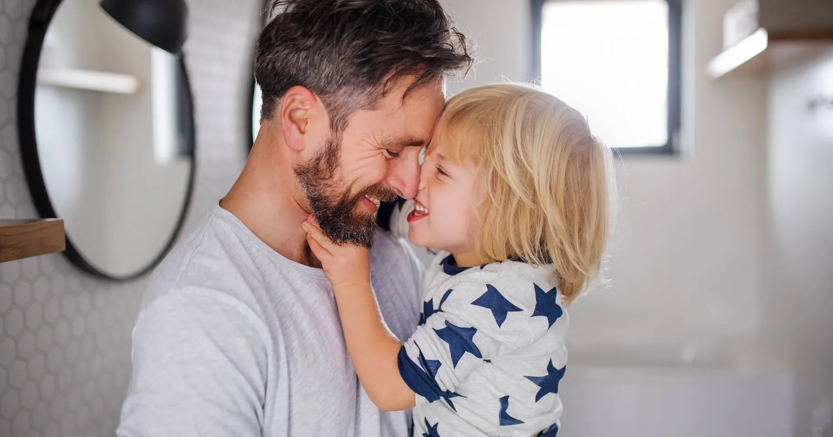un père souriant serrant son enfant souriant dans ses bras