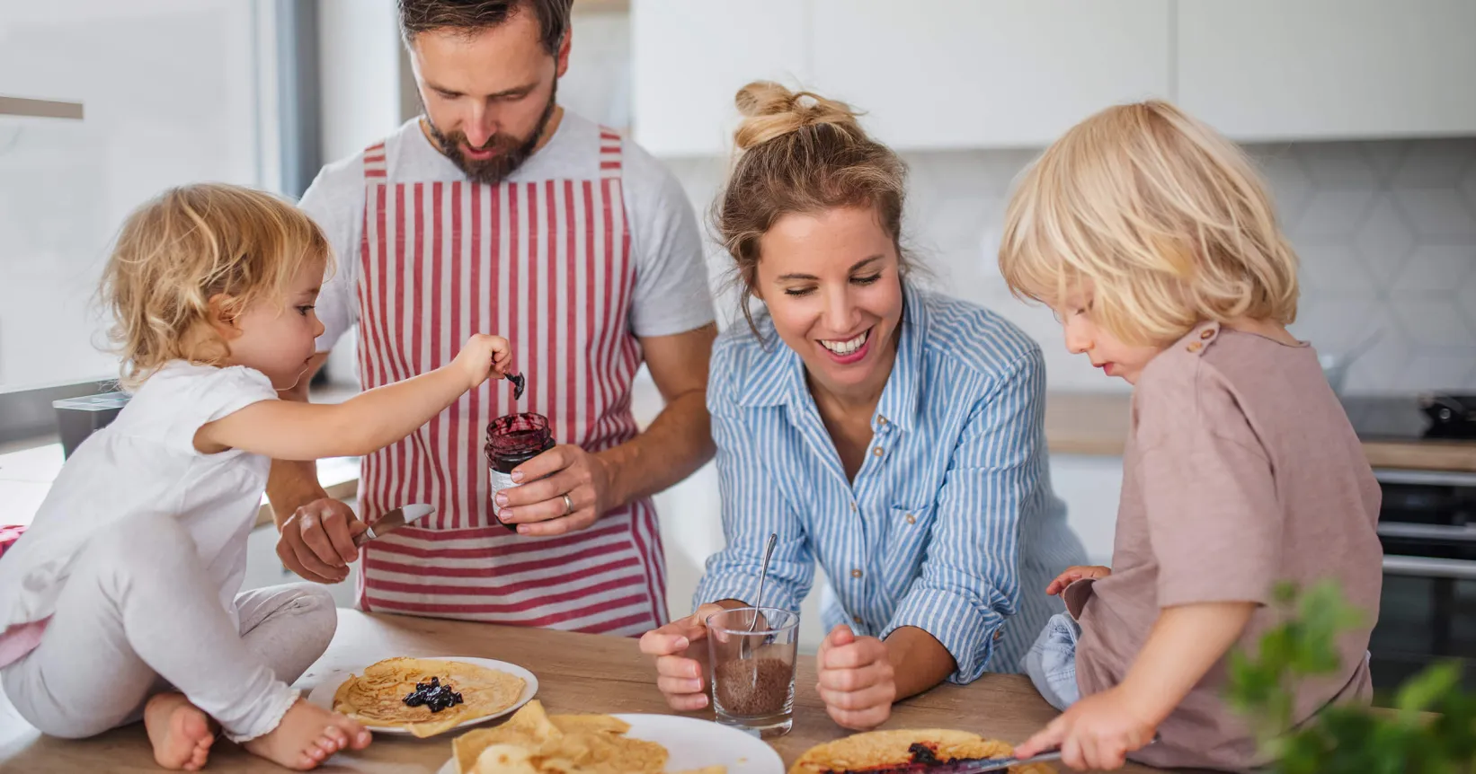 Des parents qui prennent le petit déjeuner avec leurs deux enfants.