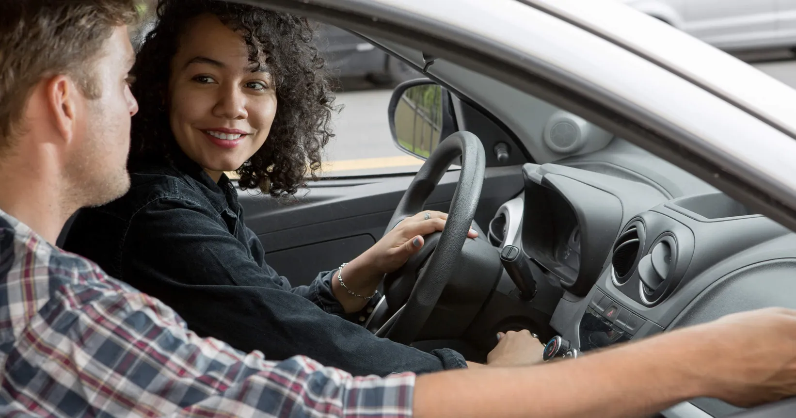 Un jeune femme conduit une voiture accompagnée d'un jeune homme