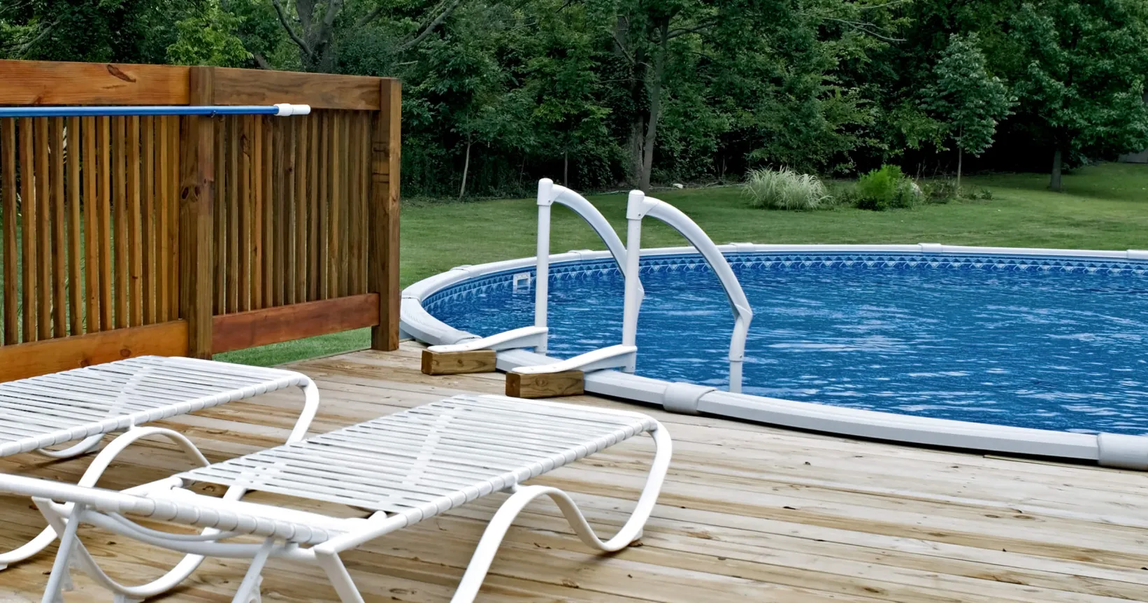 Une terrasse avec deux chaises longues et une piscine hors terre