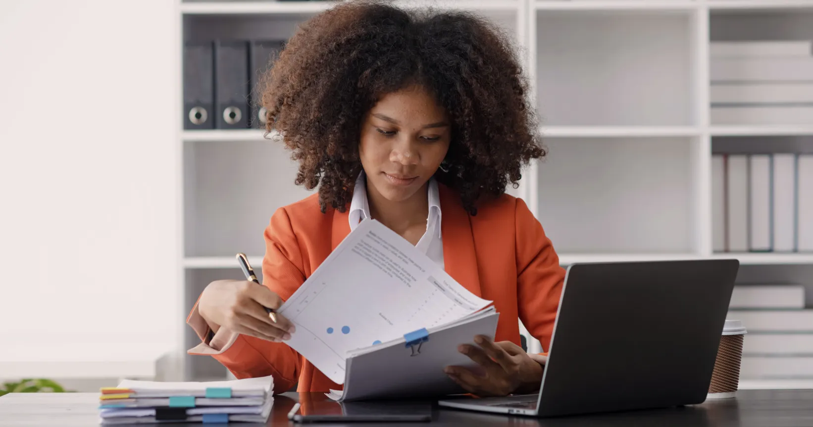 Une femme consulte des documents devant son ordinateur portable