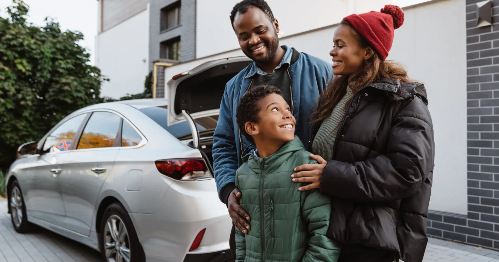 Une famille devant une voiture et une maison