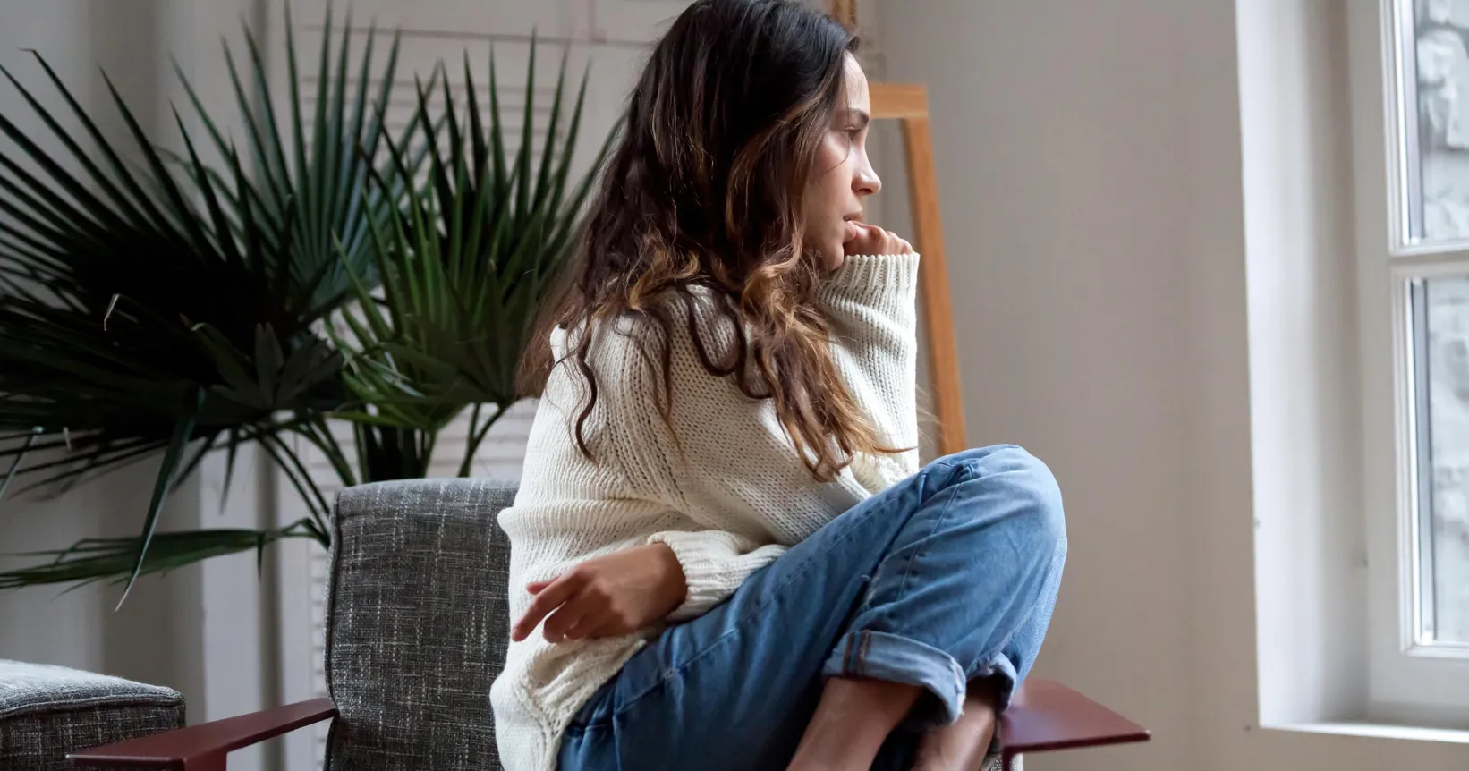 Une femme est assise et regarde par la fenêtre