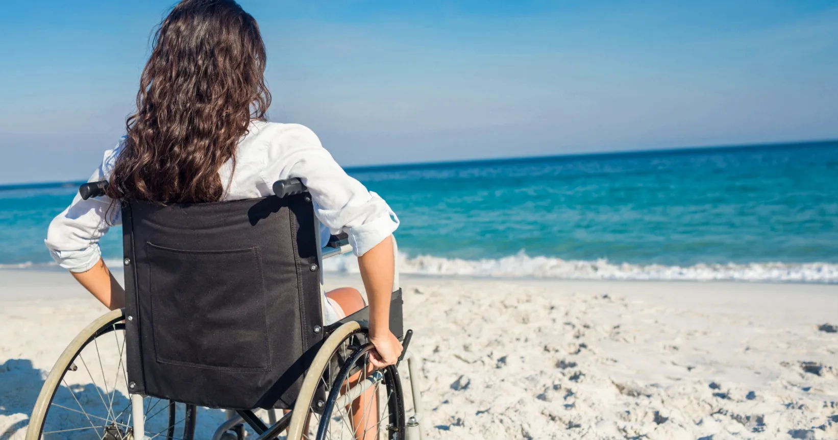 Une femme en chaise roulante sur la plage