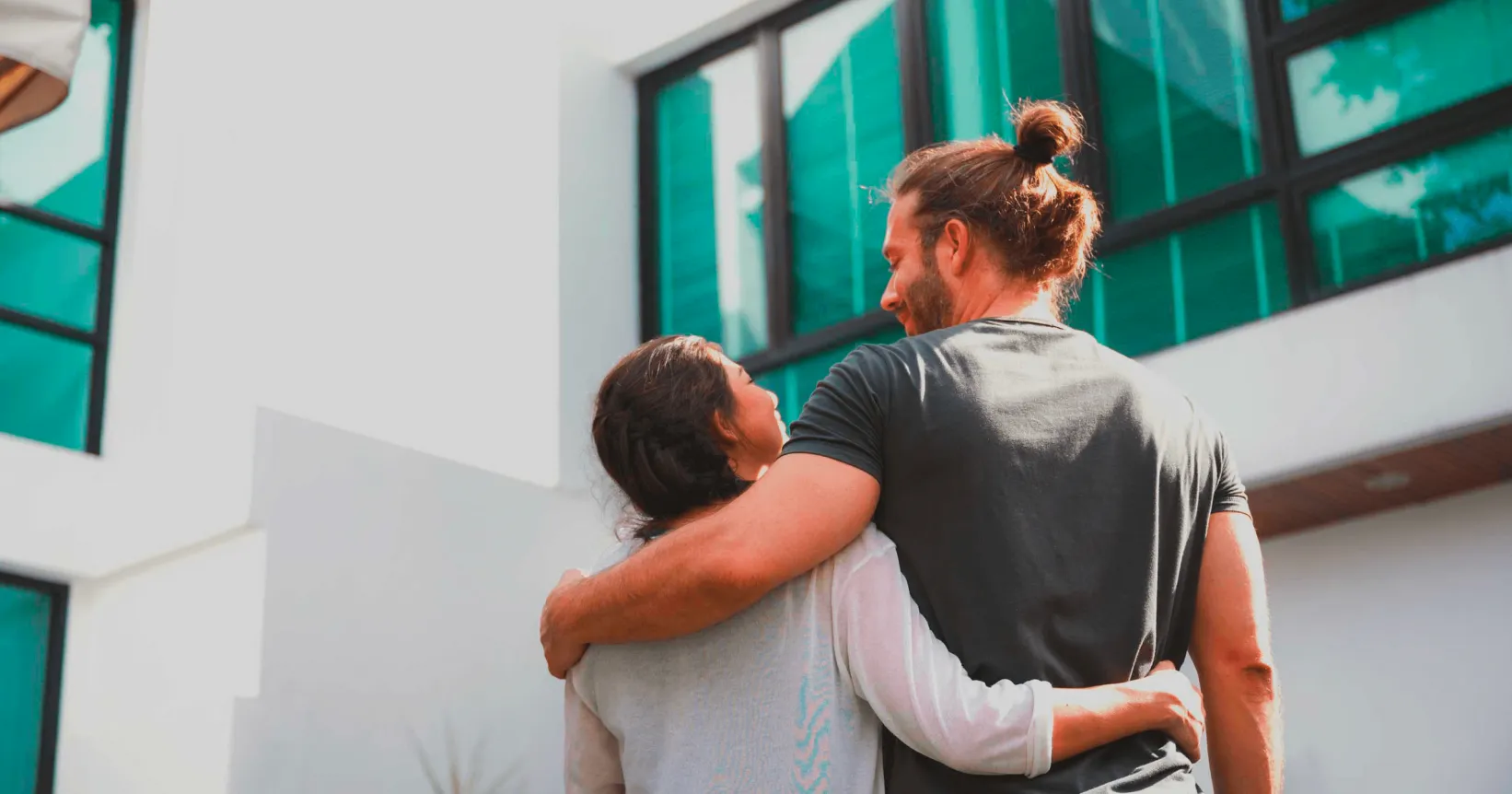 Deux personnes se tiennent par la taille devant une maison