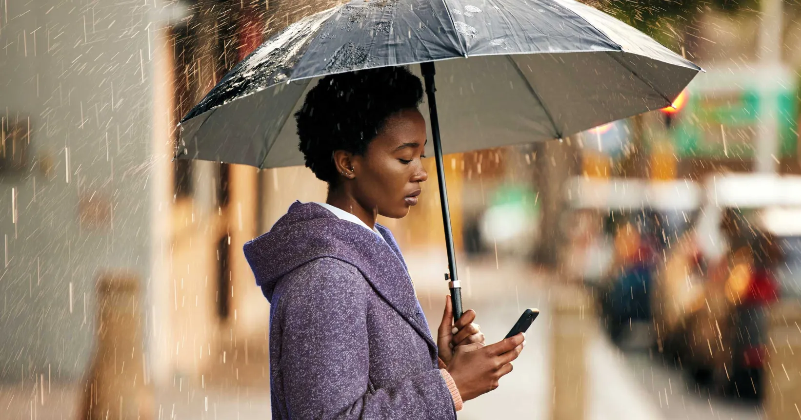 Une femme sous un parapluie tient un cellulaire