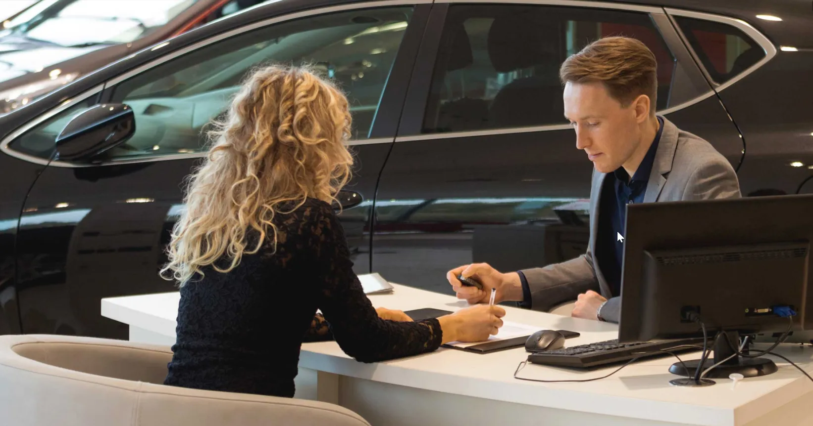 Une femme discute avec un vendeur chez un concessionnaire