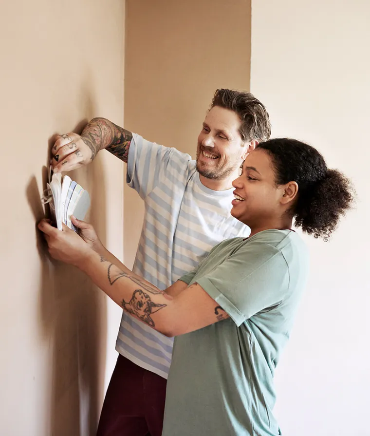 Two people standing by a wall, comparing color samples