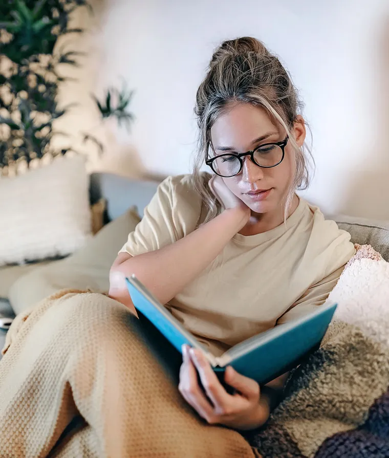 Une femme en train de se détendre avec un livre à la maison