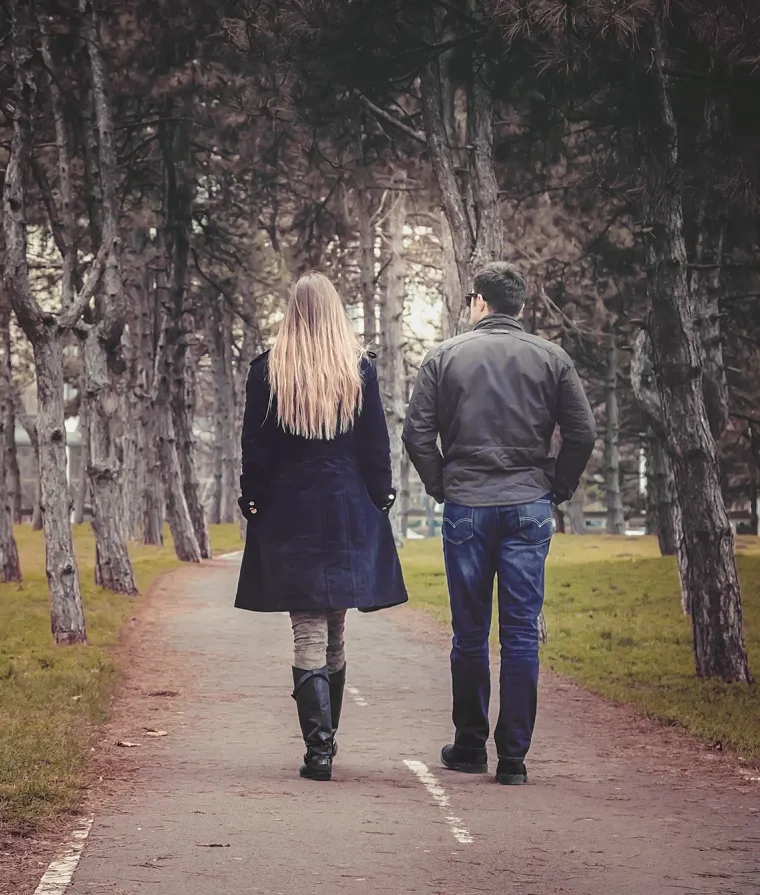 Deux personnes marchent dans un sentier boisé