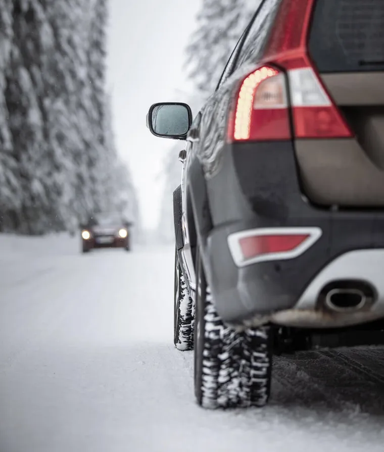 Un zoom sur les pneus d'une voiture en hiver
