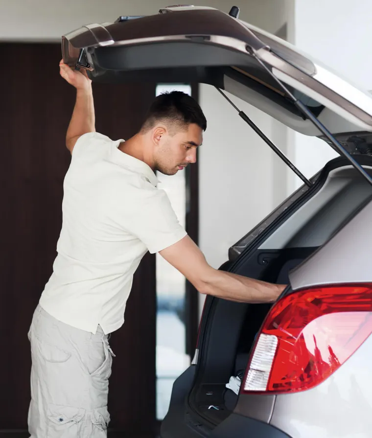 Un homme range du matériel dans le coffre d'une voiture