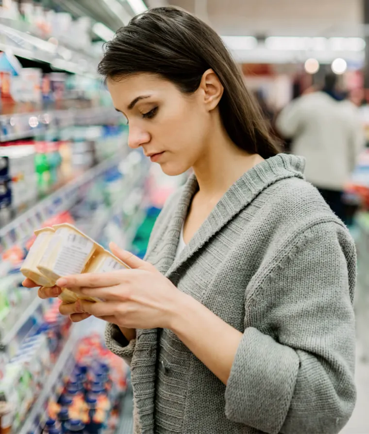 Une femme lit l'étiquette d'un produit à l'épicerie