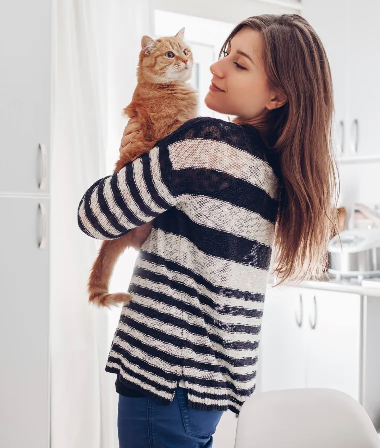 Une femme tient un chat roux dans ses bras