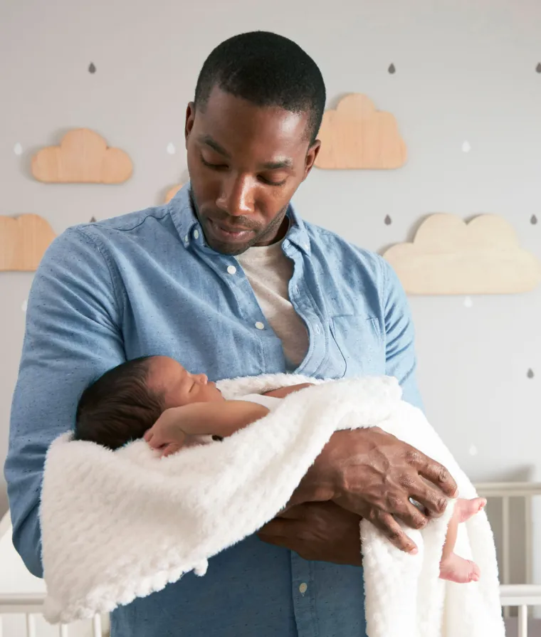 Un père tient son enfant qui dort dans ses bras
