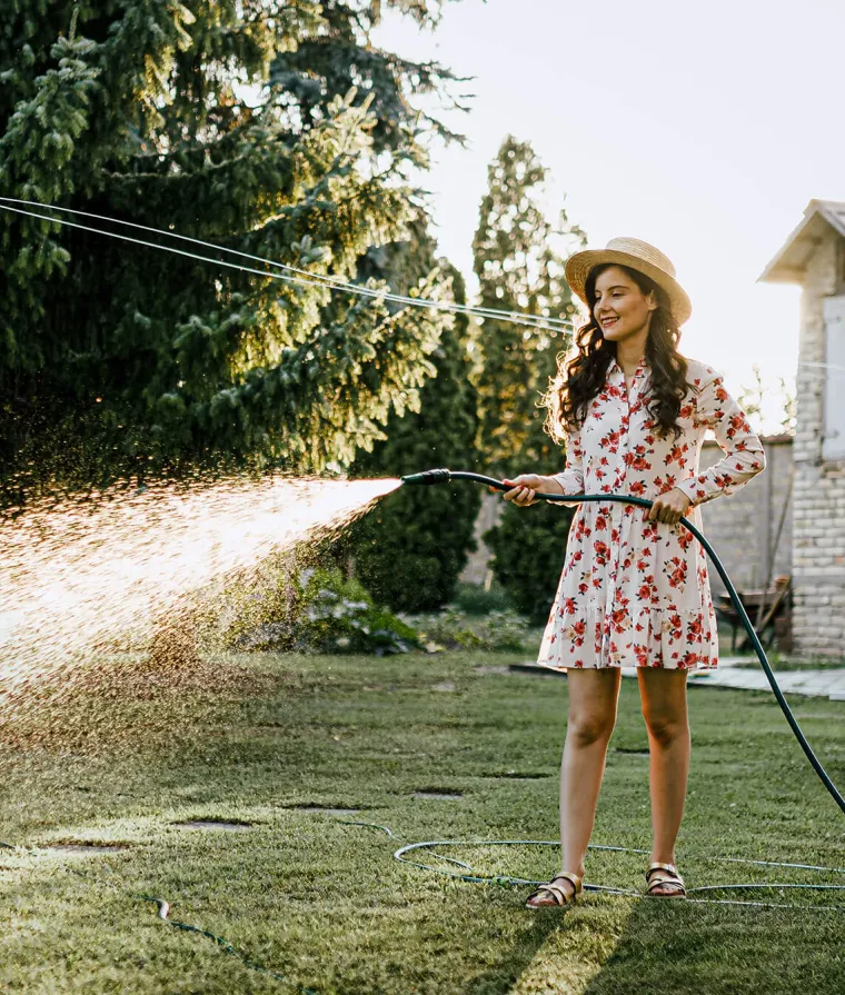 Une femme arrose son gazon