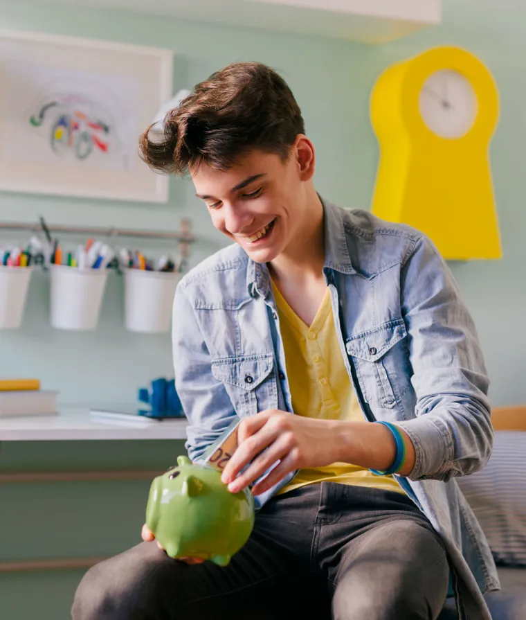 Un jeune homme tient une tirelire dans ses mains