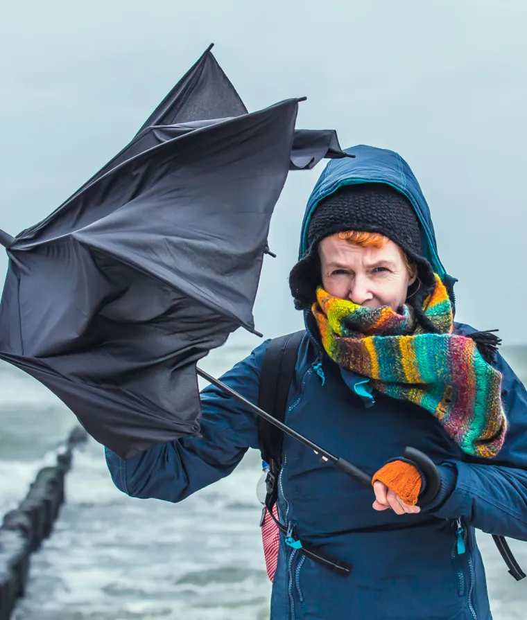 Une femme tient un parapluie dans de forts vents