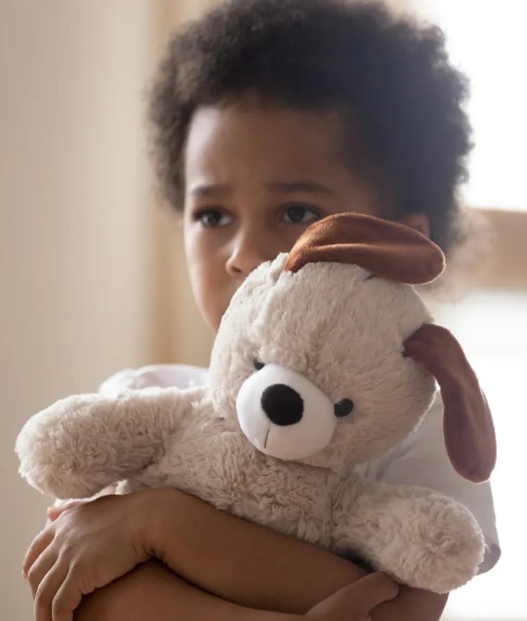 Un enfant tient une peluche dans ses bras