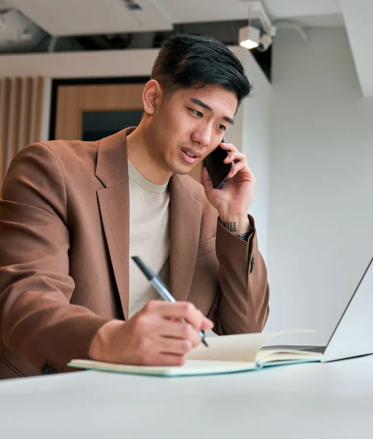 Un homme est au téléphone devant son ordinateur portable