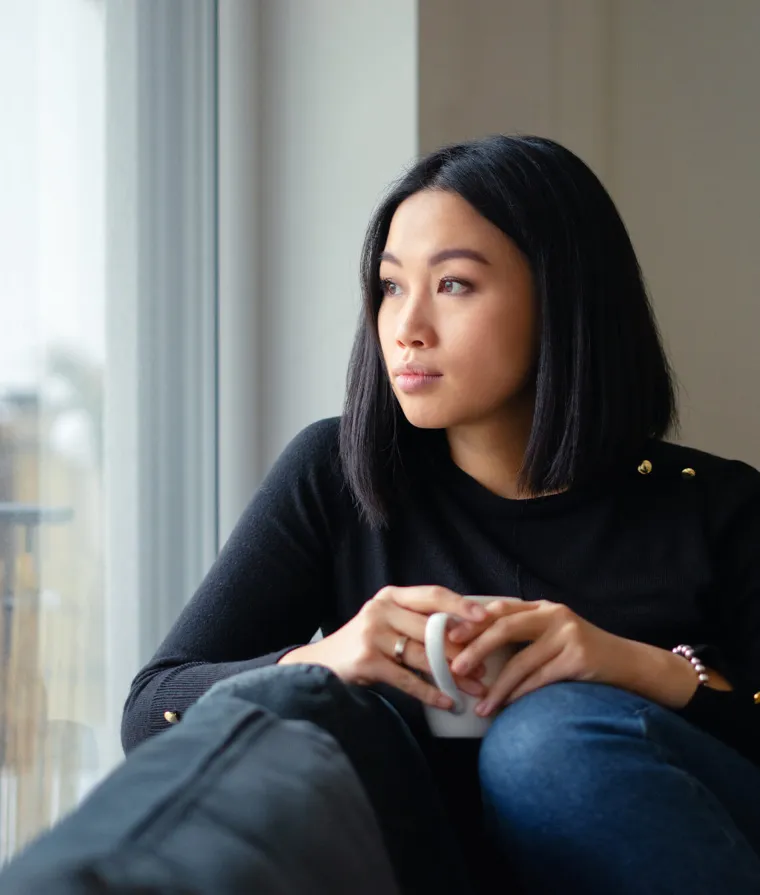 Une femme assise sur un fauteuil regarde par la fenêtre