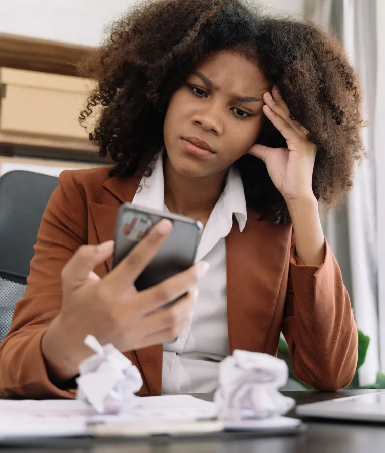 Une femme fronce les sourcils en regardant son téléphone portable
