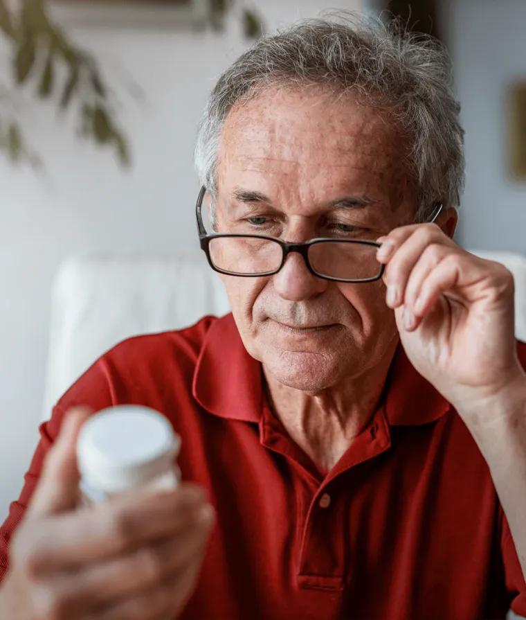 Un homme âgé regarde un contenant de médicaments
