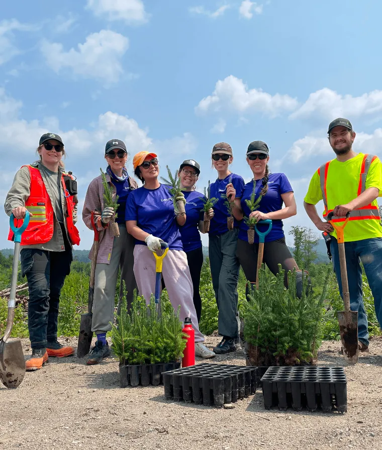 Group of people holding shovels and plants