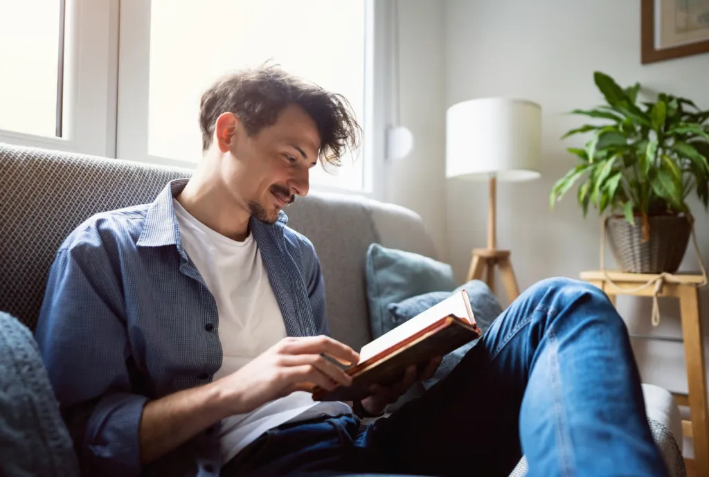 Un homme lit un livre sur un canapé